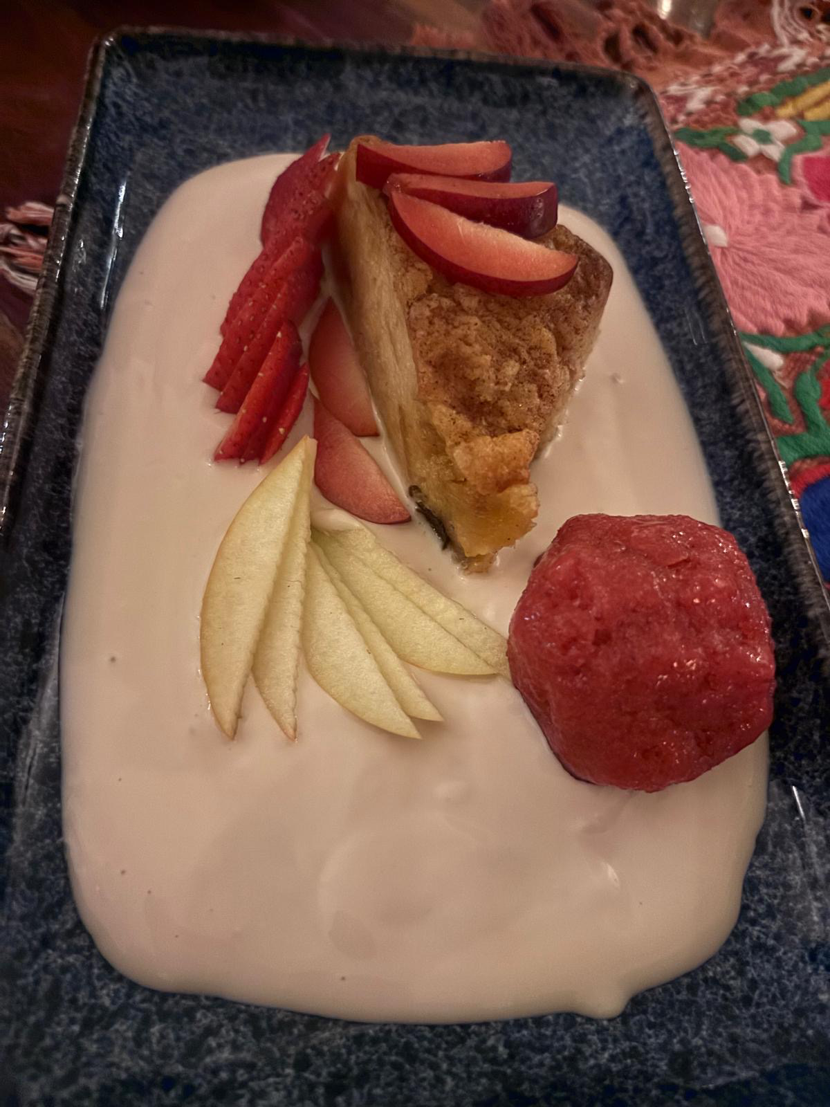 Slice of cake with fresh fruit and a scoop of sorbet on a pool of cream at Cetli