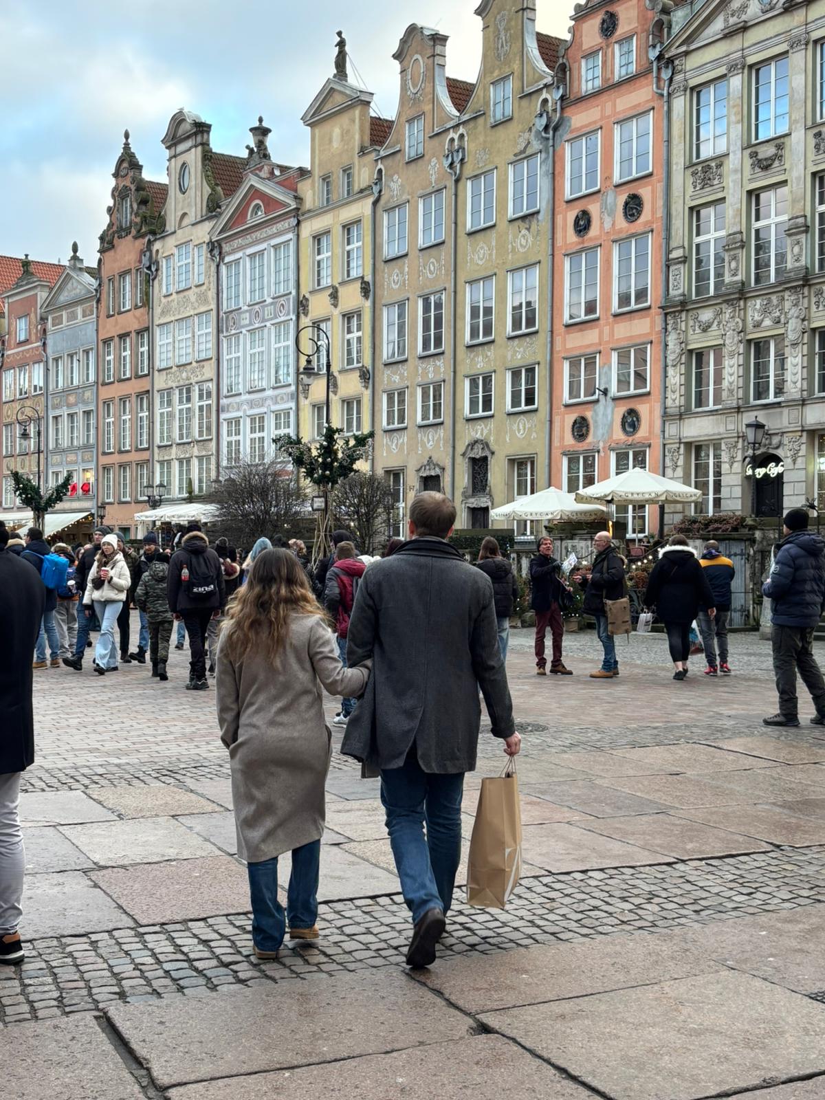 Couple walking down Gdansk's Long Street past colourful gabled houses
