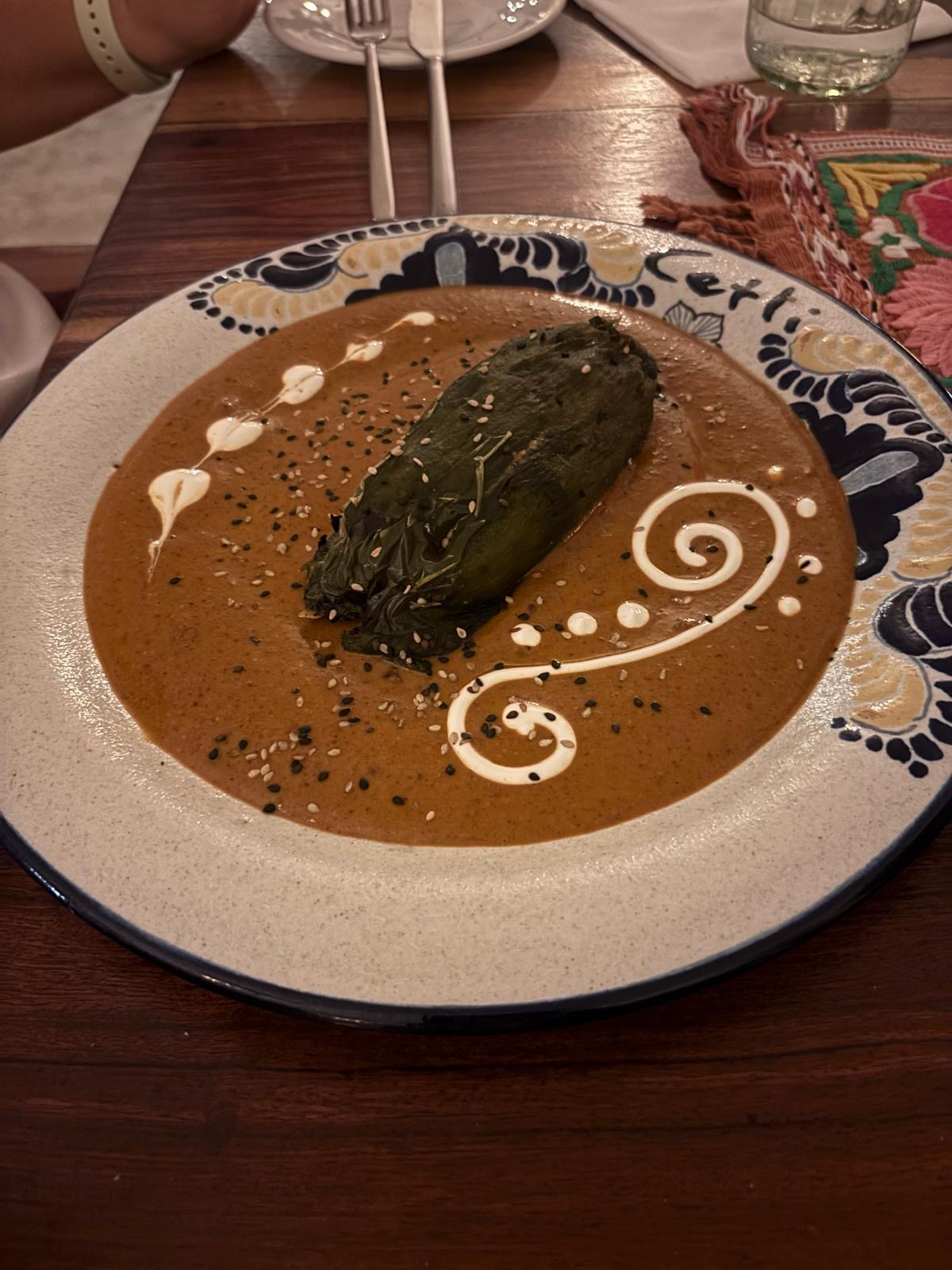 Stuffed pepper in rich mole sauce with sesame seeds and cream swirl at Cetli